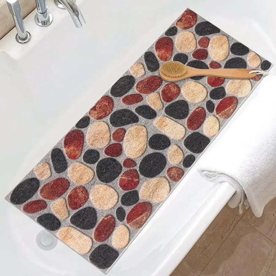 Bath mat with a pebble design placed beside a bathtub on tiled flooring.