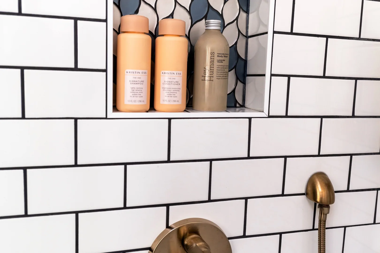Recessed shower niche holding toiletries in a white tiled wall.