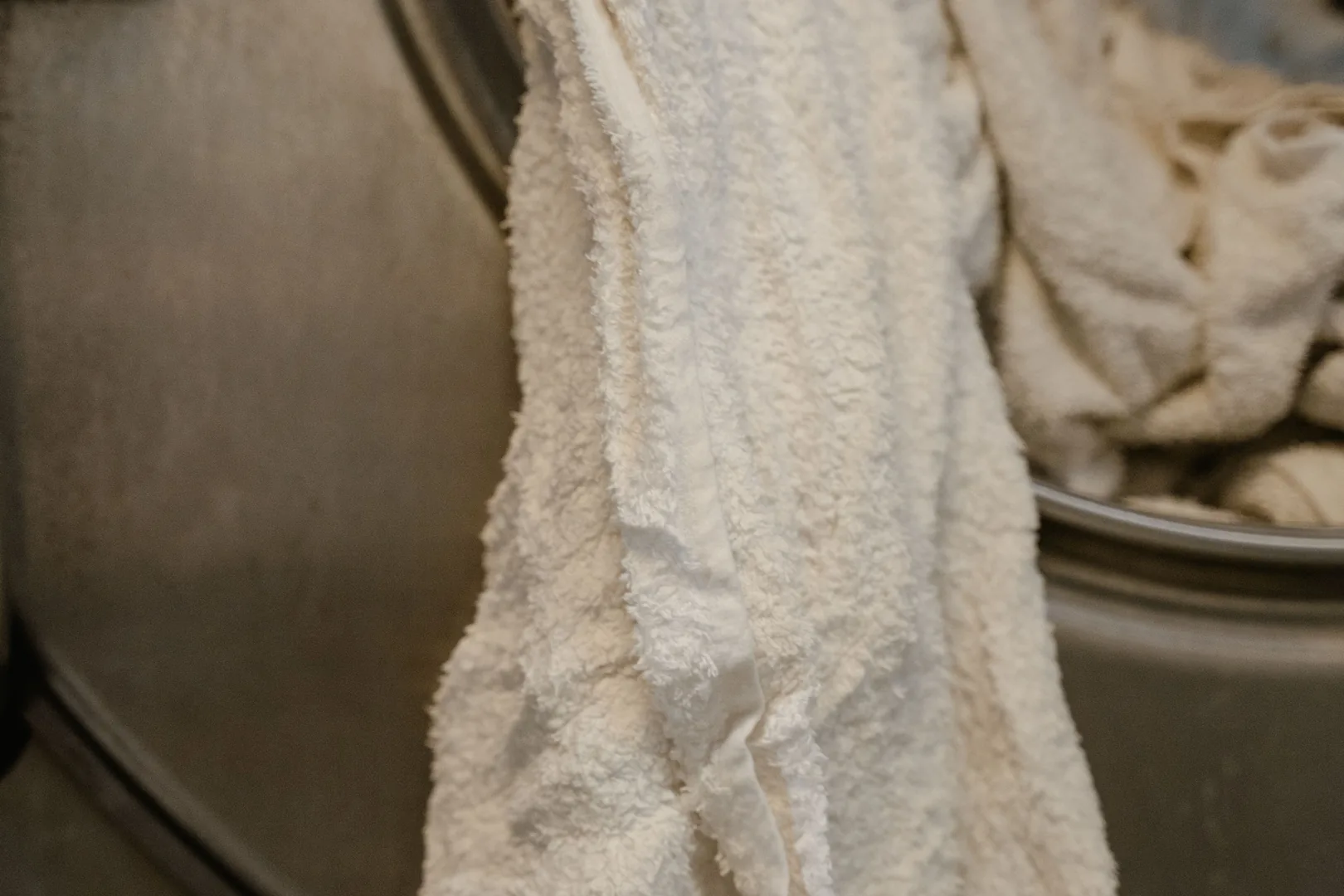 White towels being removed from a front-loading washing machine.