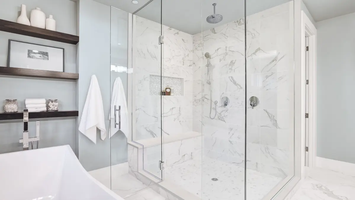 Bright bathroom featuring a glass shower, marble tiles, and modern fixtures.