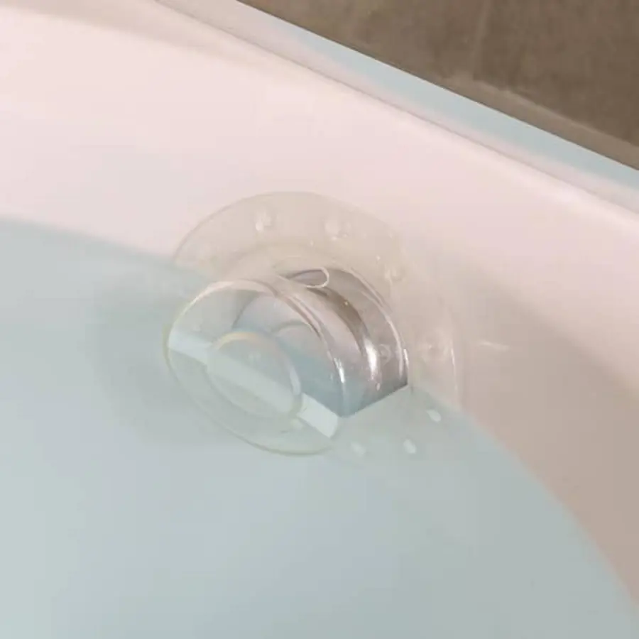 Clear bathtub overflow cover installed in a bathtub with water.