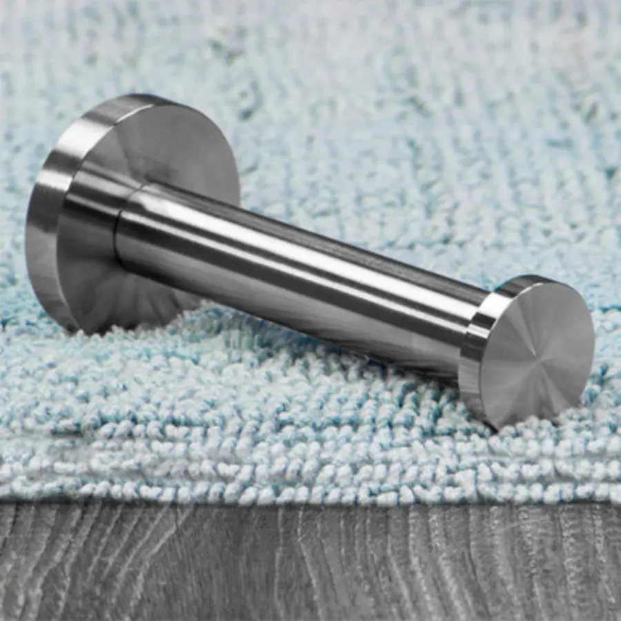 Metal toilet paper holder base resting on a textured surface.