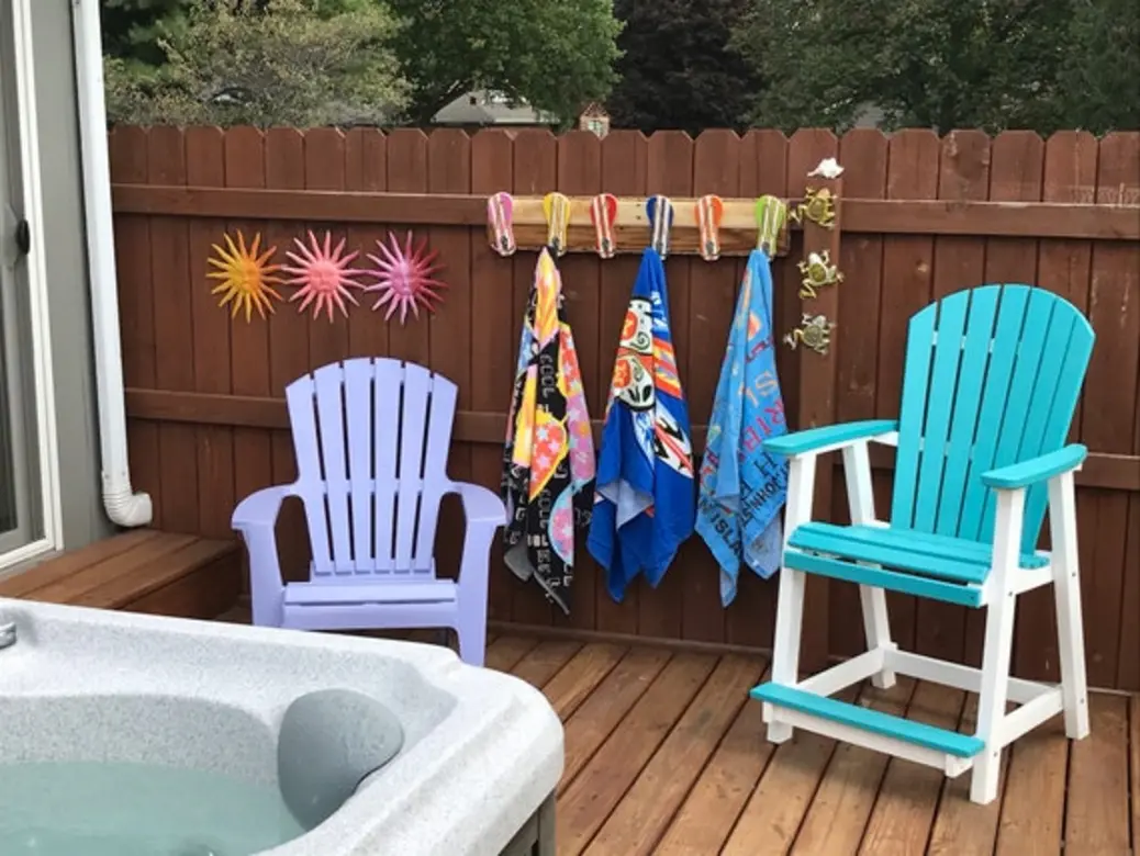 Colorful towels hanging on hooks next to purple and teal chairs near a hot tub.