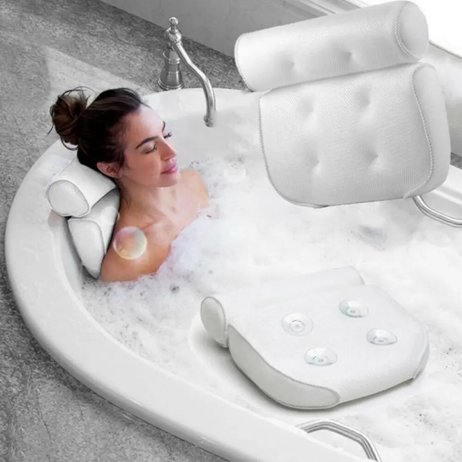 A woman relaxing in a bubble bath with a white bath pillow and backrest.