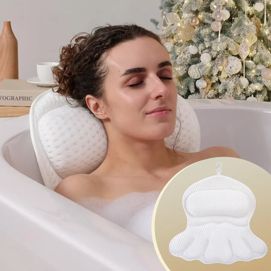 A woman relaxes in a bathtub with a white bath pillow supporting her head.