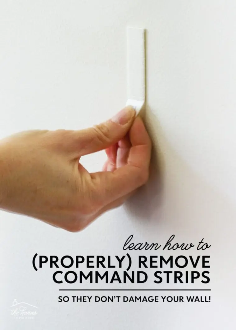 A hand demonstrating how to pull a command strip straight down from a wall.