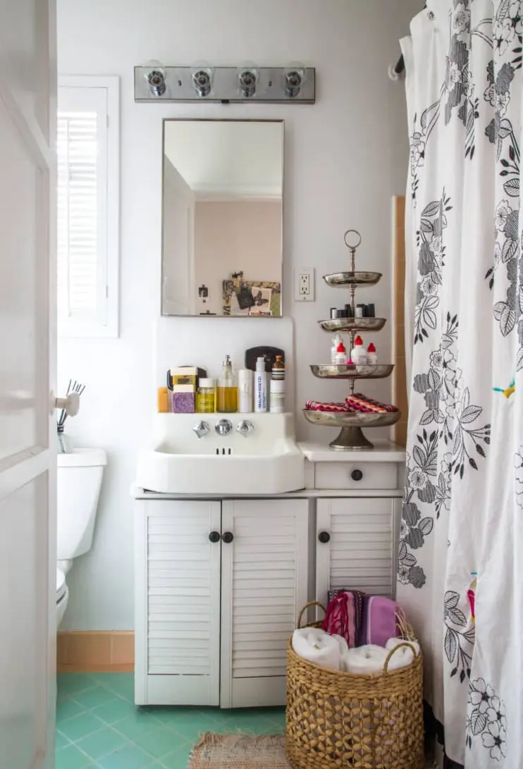 Bright bathroom featuring a white sink, decorative shower curtain, and tiered storage stand.