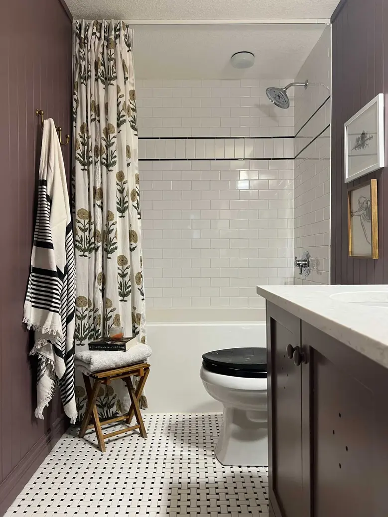 Bathroom featuring a shower with a patterned curtain, a toilet, and a sink with dark cabinetry.